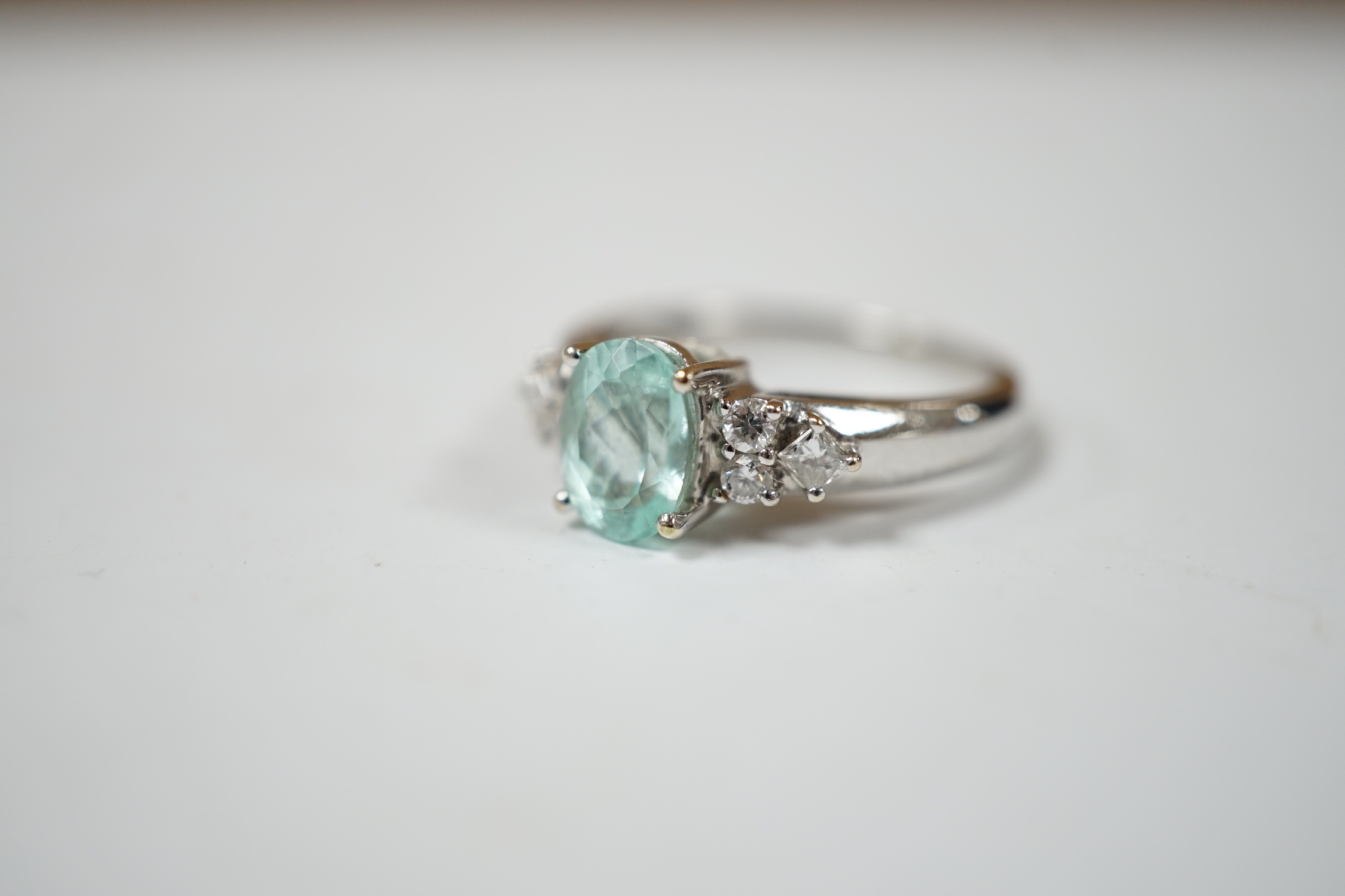A modern 18ct gold and oval cut paraiba tourmaline set dress ring with six stone diamond set shoulders, size O, gross weight 4.9 grams.